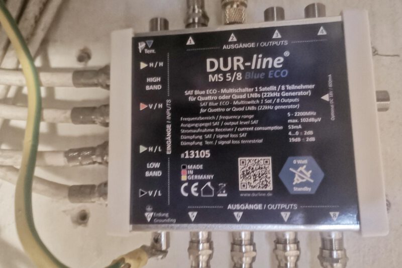SAT-Multiswitch von der Firma DUR-line an der Wand. 6 Anschlüsse sind belegt, Erdungskabel ist angeschlossen