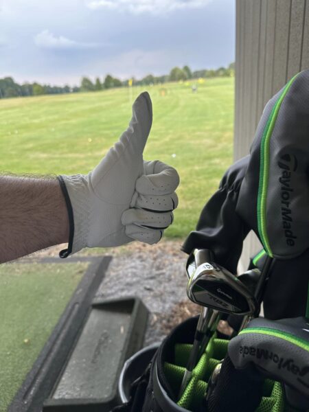 Hand im weißen Golfhandschuh und zeigt Daumen nach oben