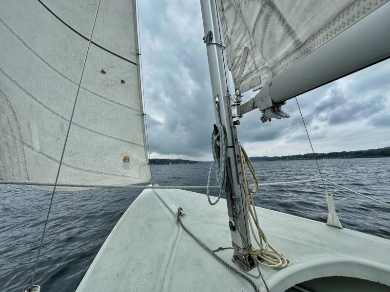 Während der Fahrt auf einem weißen Segelboot nach vorne fotografiert. Blick auf dem Möhnesee bei bewölktem Himmel